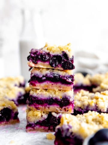 Stack of vegan lemon blueberry bars in front of a jug of milk.