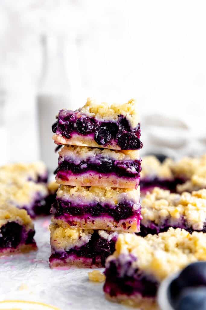 Stack of vegan lemon blueberry bars in front of a jug of milk.