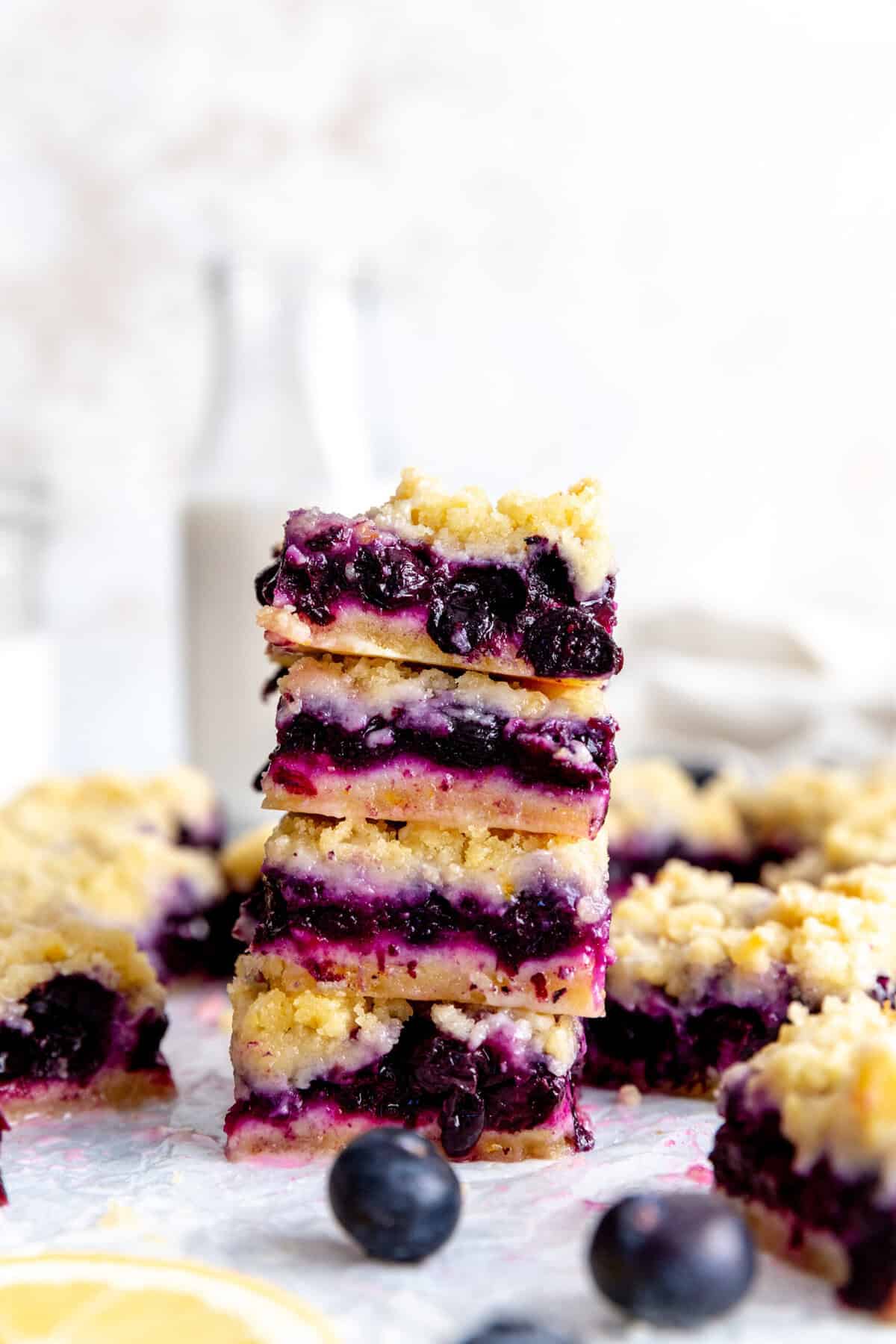 Stack of vegan lemon blueberry bars in front of a jug of milk.