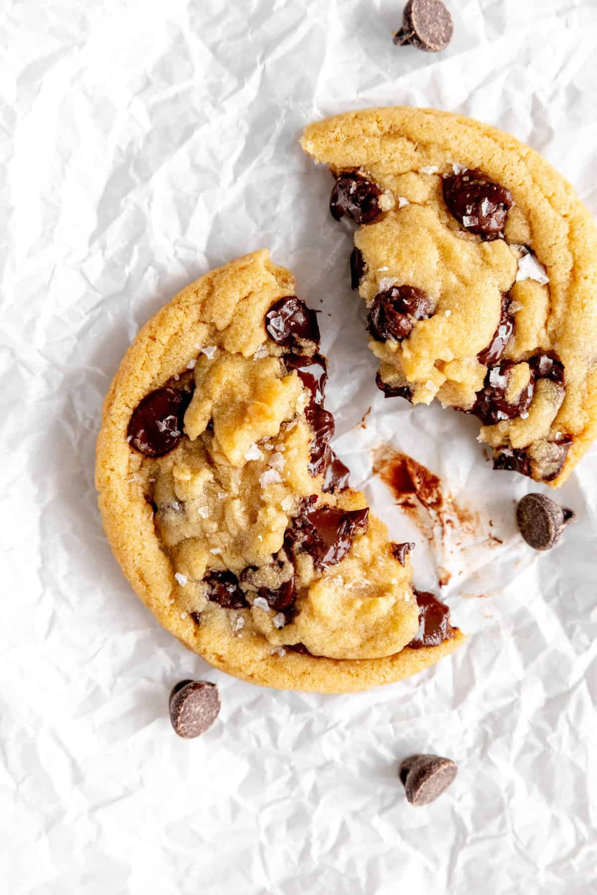 Two chocolate chip cookie halves surrounded by chocolate chips.