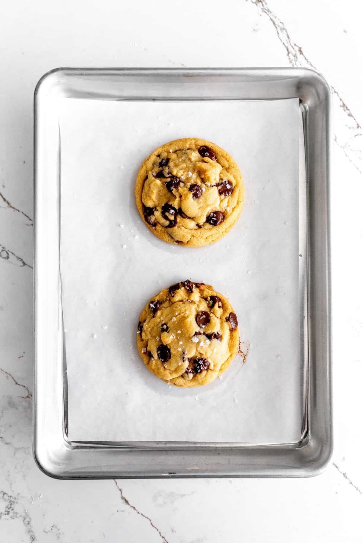 Baked chocolate chip cookies on a small baking sheet.