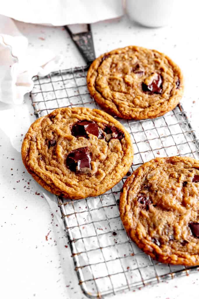 Toffee chocolate chip cookies on a wire rack and a jug of milk.