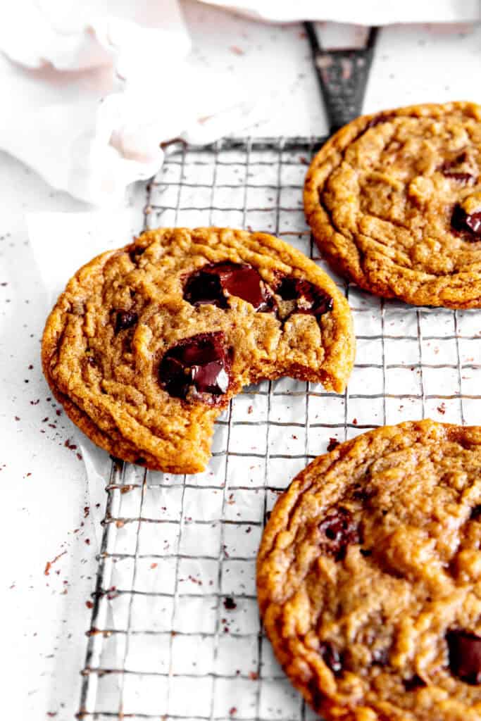 Toffee chocolate chip cookie with a bite taken out of it on a wire rack.