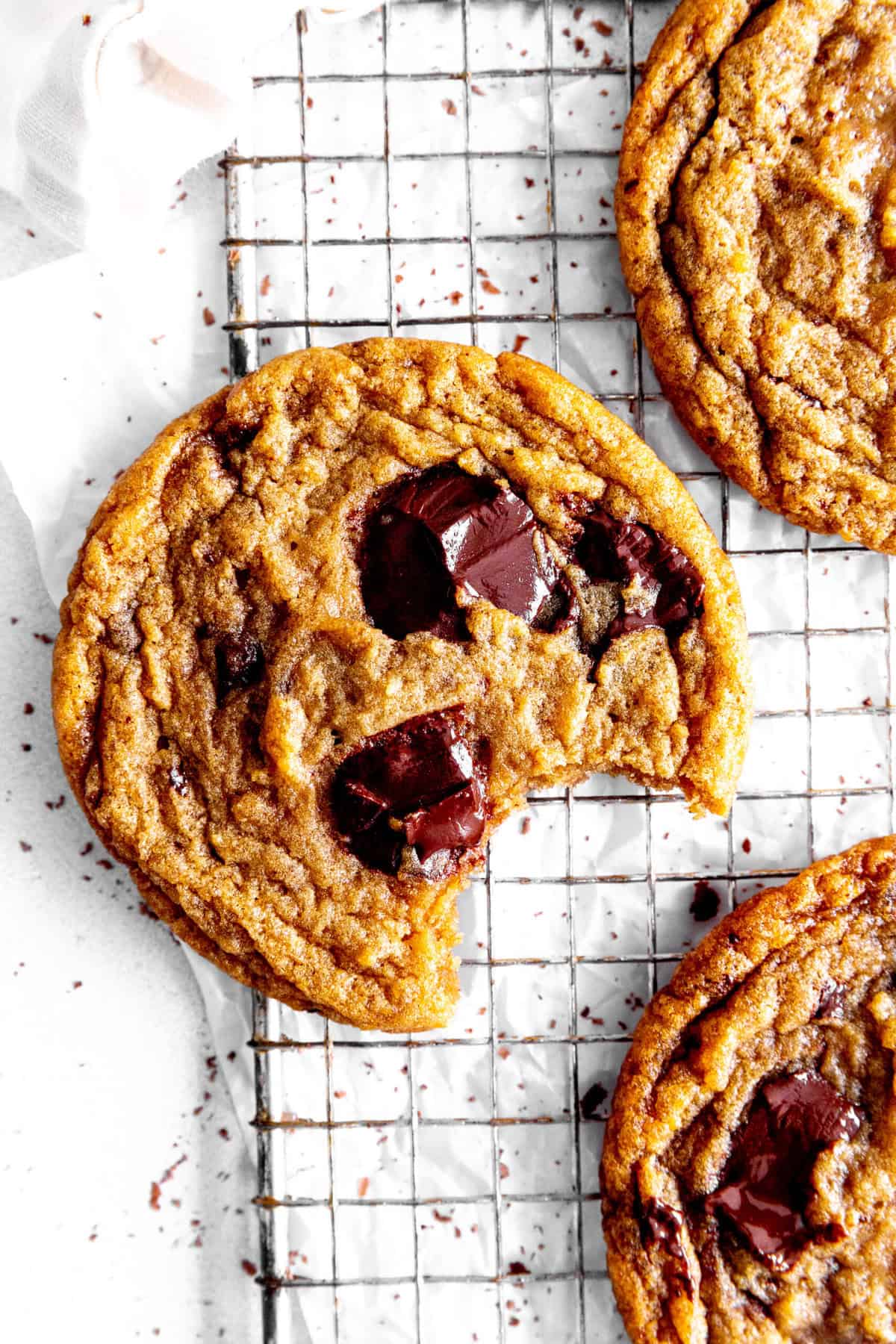 Toffee chocolate chip cookie with a bite taken out of it on a wire rack.