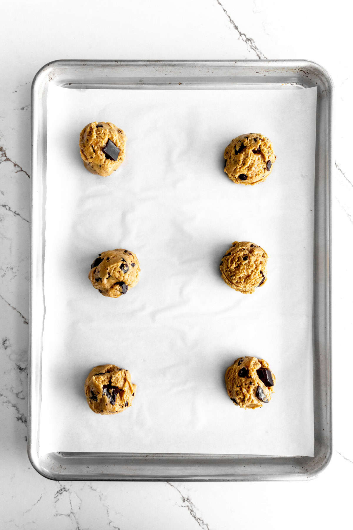 Unbaked toffee chocolate chips cookies on a baking sheet.