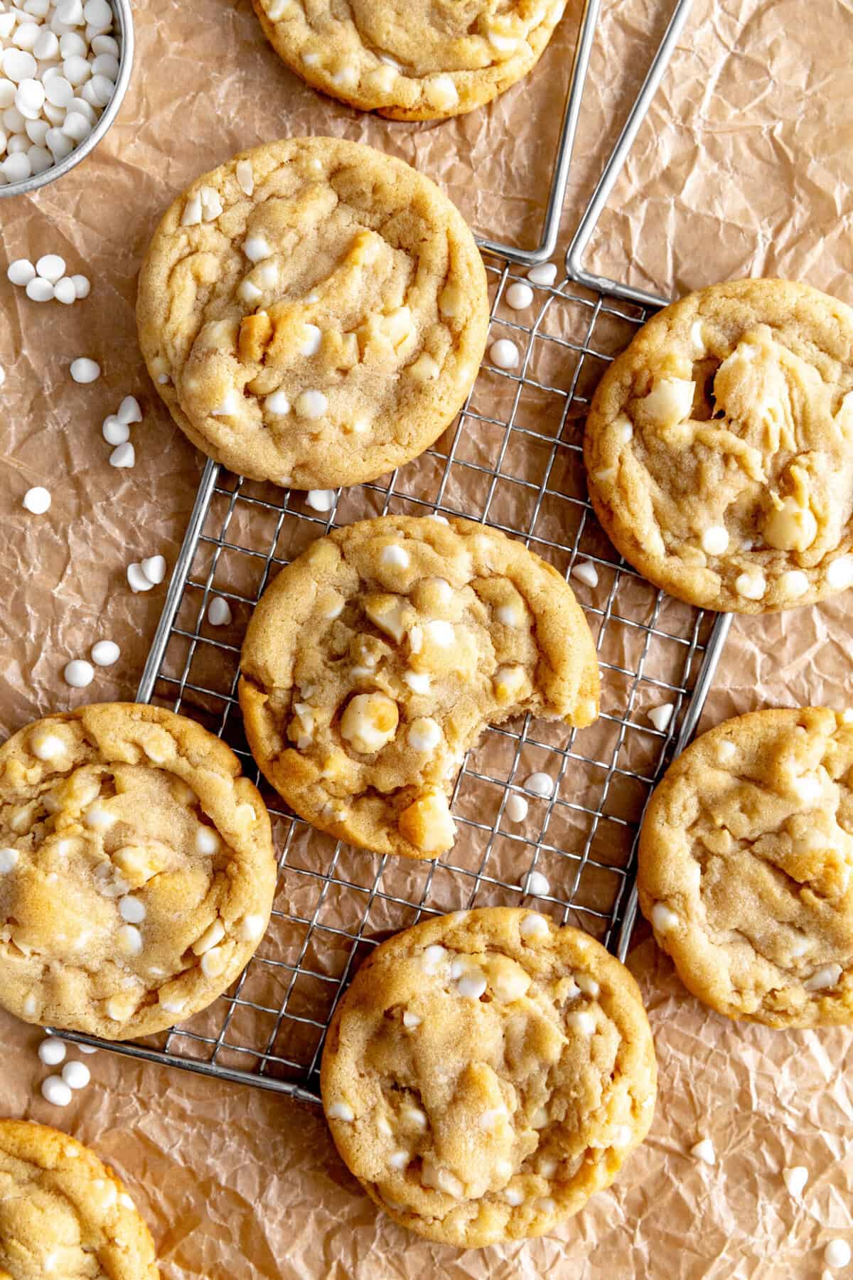 White chocolate macadamia cookies on a wire rack and brown parchment paper.