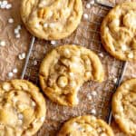 White chocolate macadamia cookies on a wire rack and brown parchment paper.