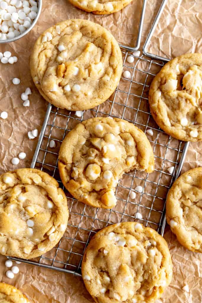 White chocolate macadamia cookies on a wire rack and brown parchment paper.