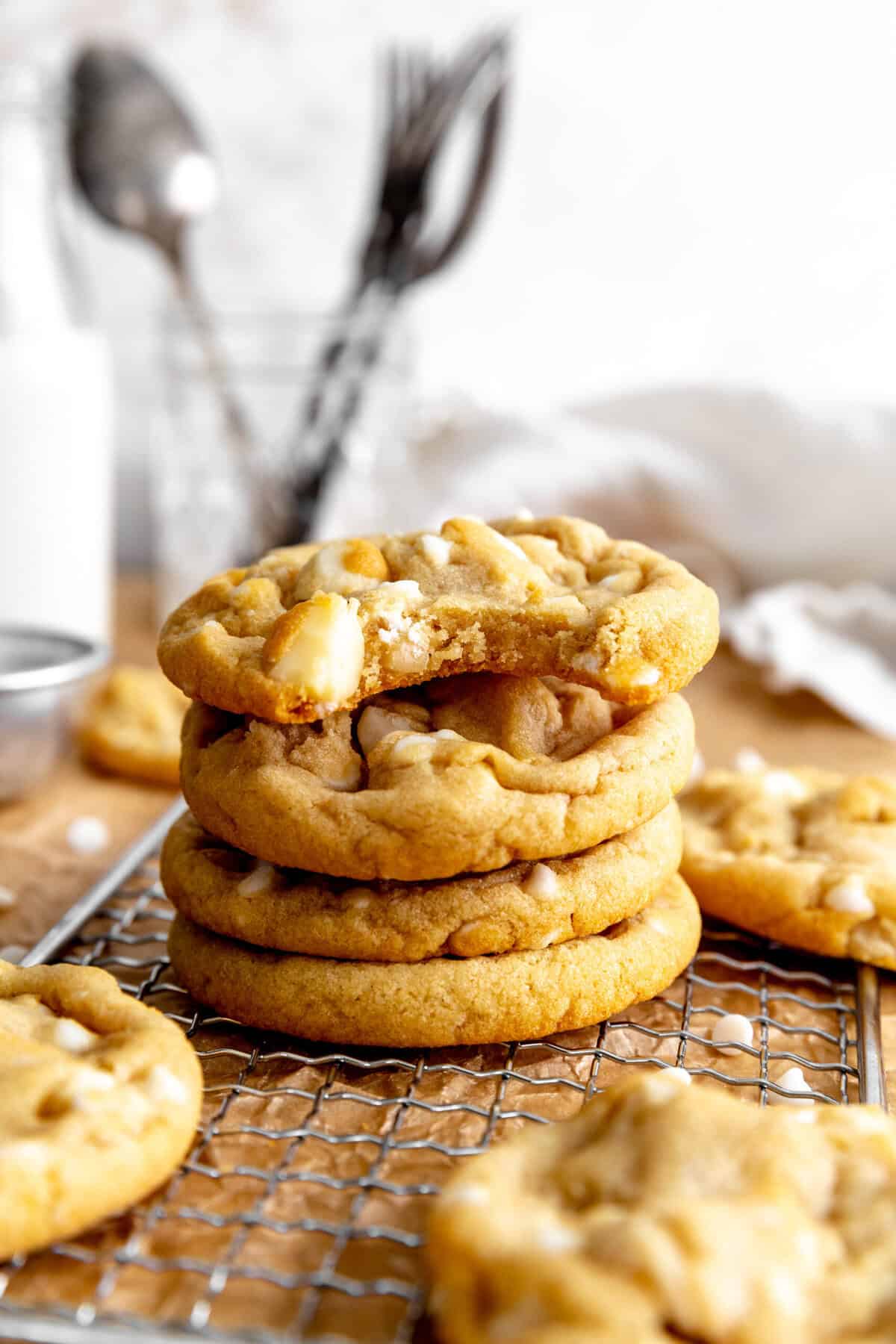 White chocolate macadamia cookie with a bite taken out of it on top of a stack of cookies.