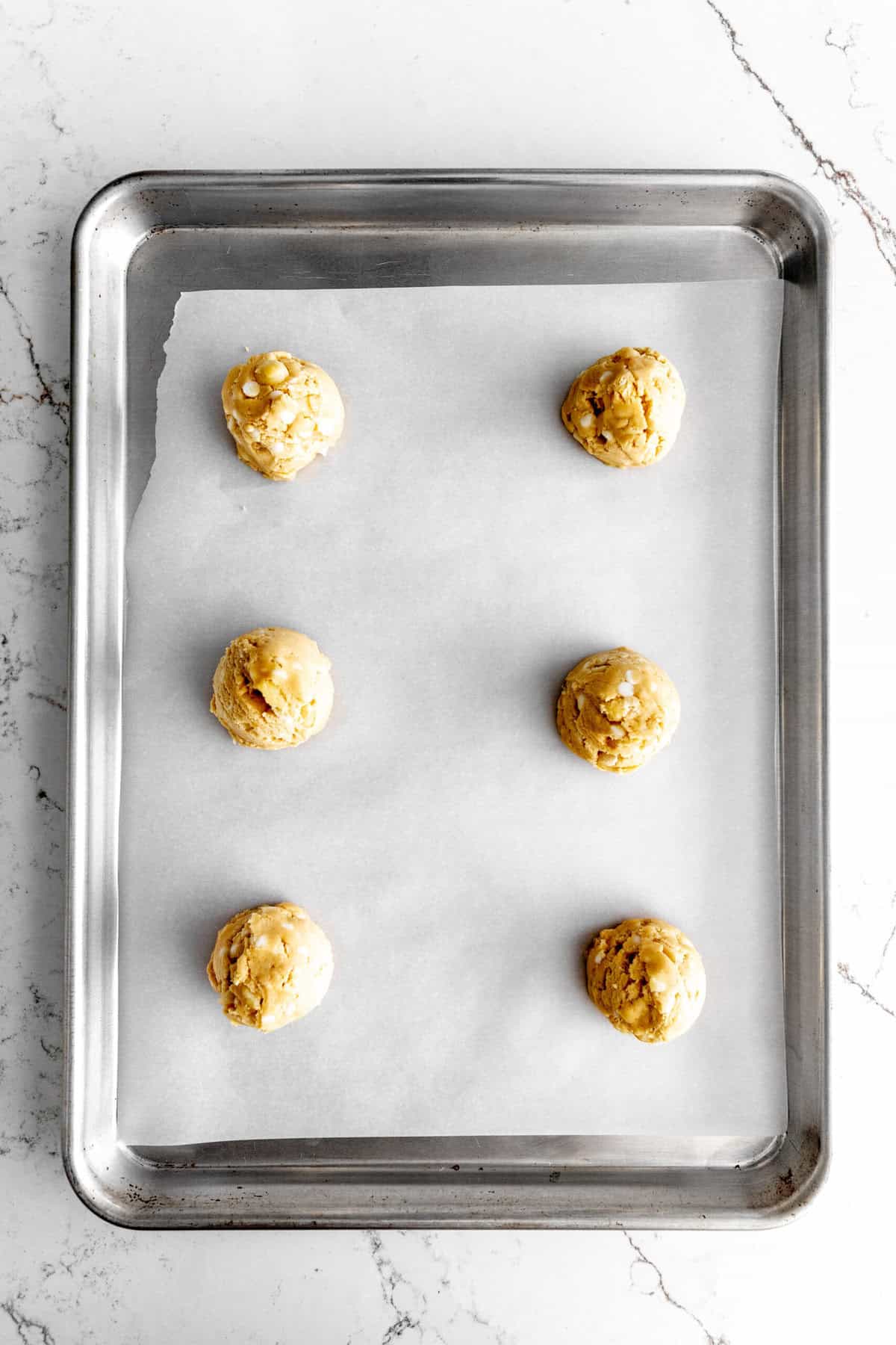 Unbaked vegan white chocolate macadamia cookies on a baking sheet.