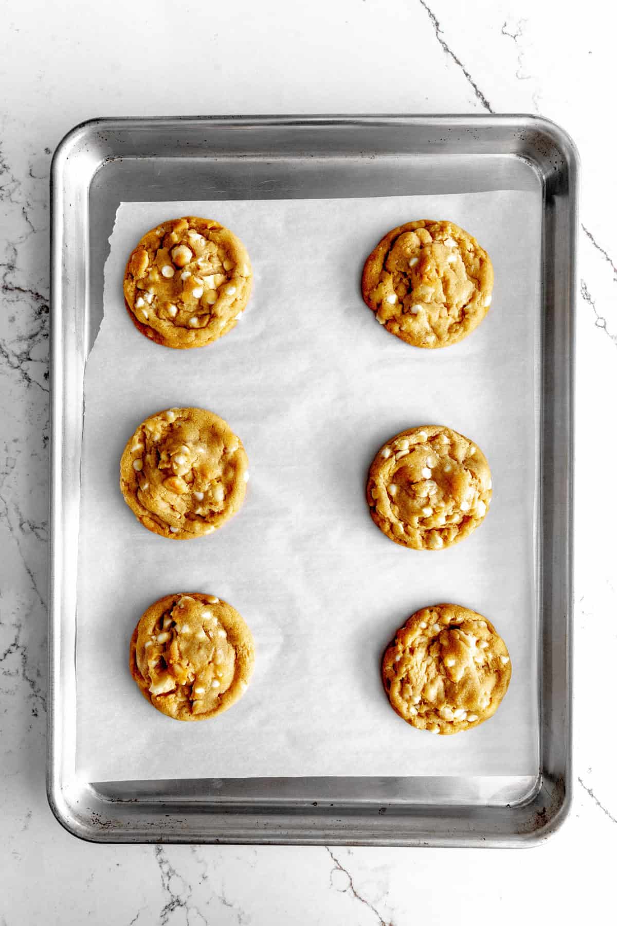 Baked vegan white chocolate macadamia cookies on a baking sheet.