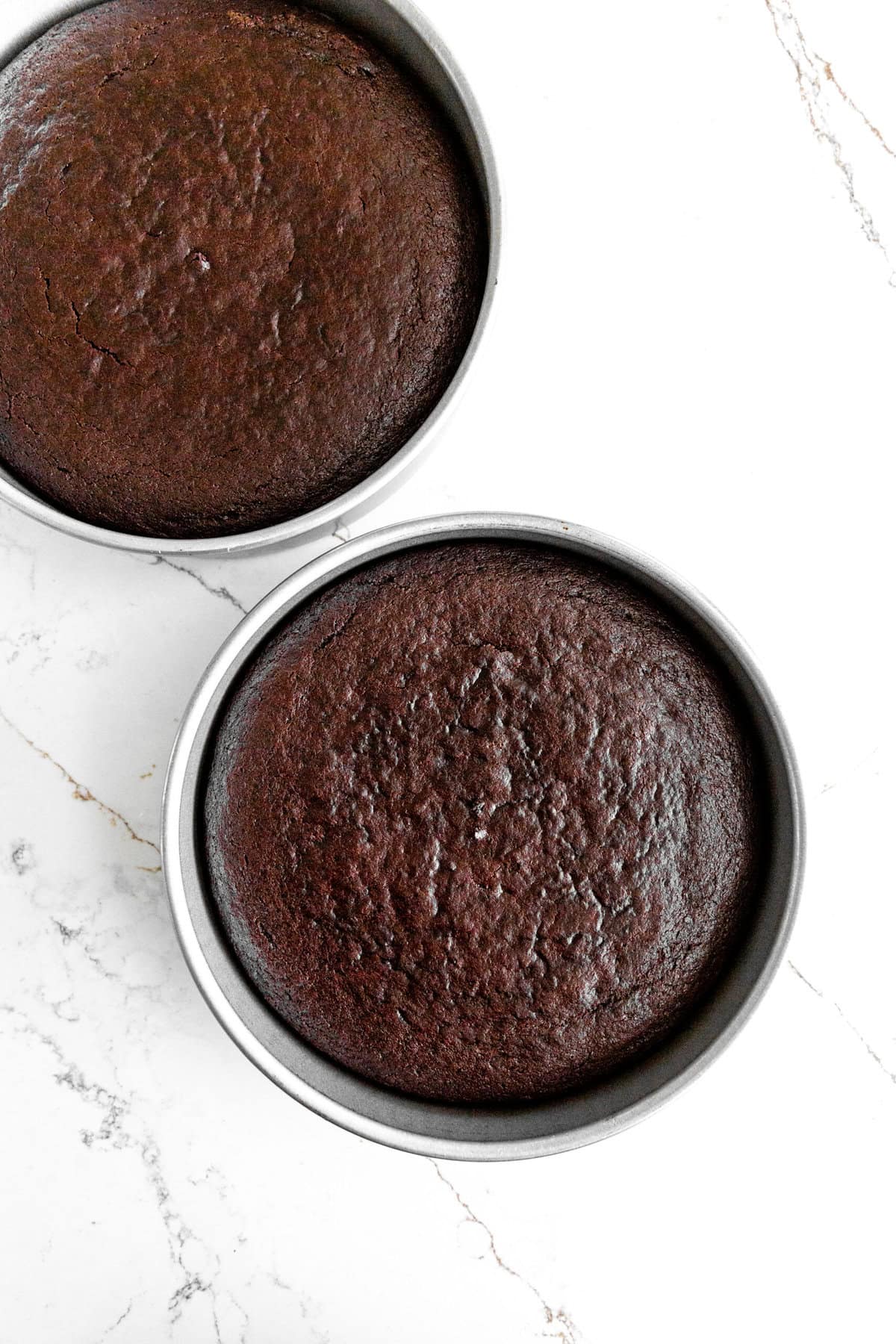 Two round pans of baked chocolate cake layers.