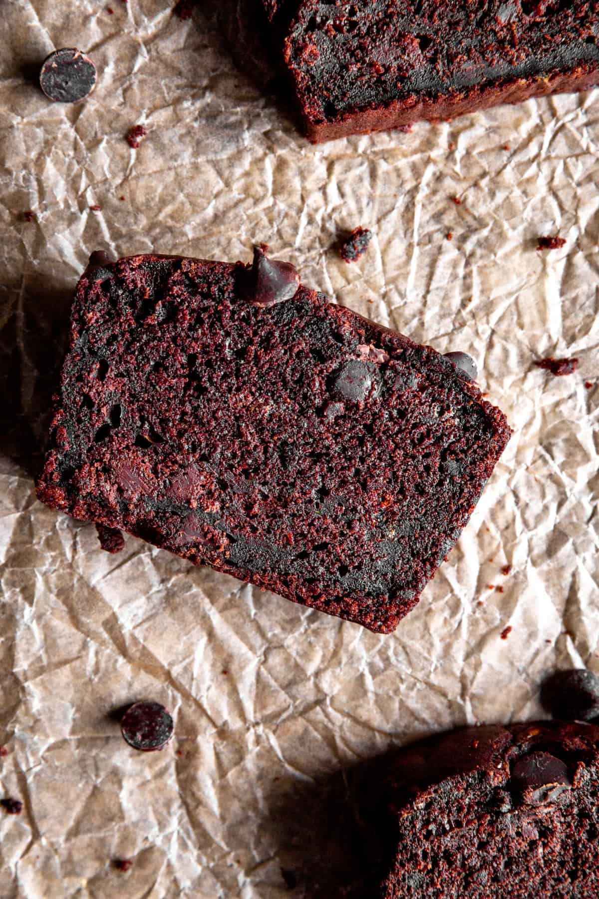 Slices of chocolate zucchini bread on a piece of brown parchment paper.