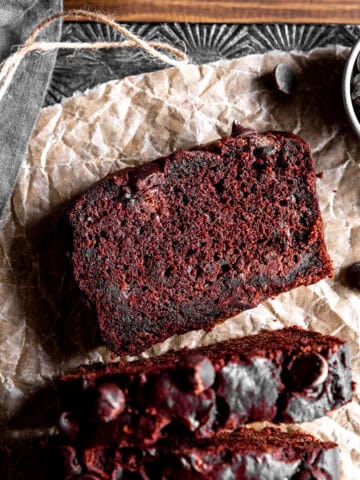 Slice of chocolate zucchini bread on a sheet of parchment paper.