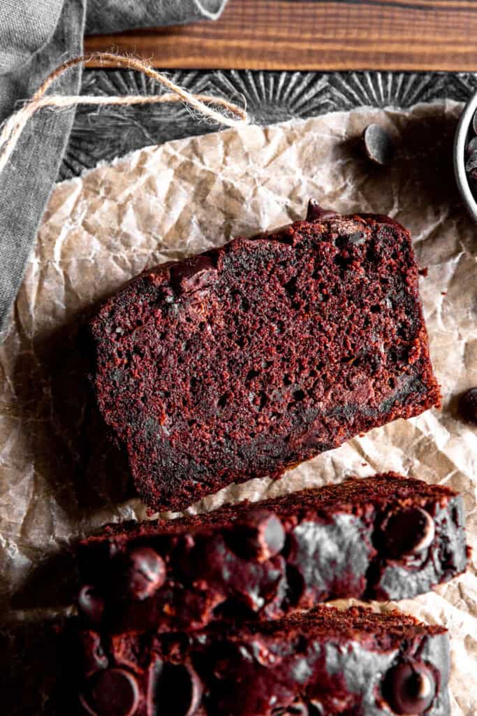 Slice of chocolate zucchini bread on a sheet of parchment paper.