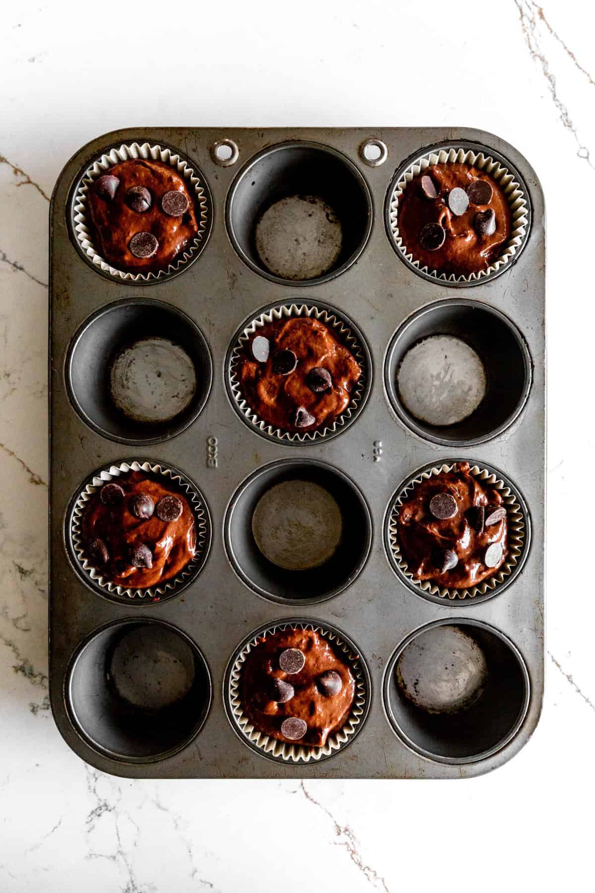 Unbaked chocolate muffins in a cupcake pan.