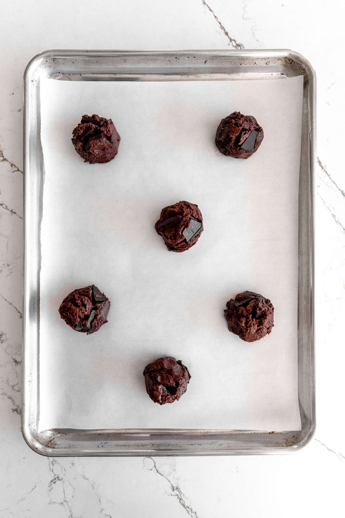 Unbaked orange chocolate cookies on a baking sheet.