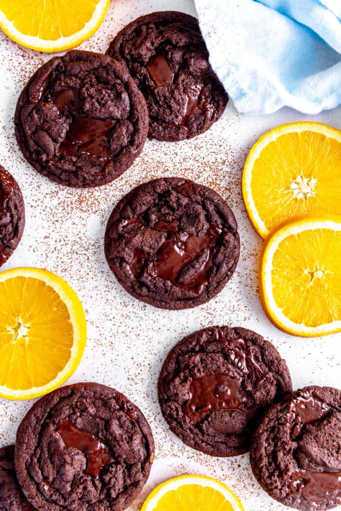 Orange chocolate cookies, fresh orange slices and a blue linen napkin on a white background.