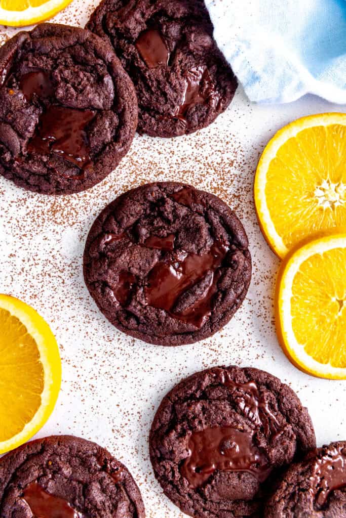 Orange chocolate cookies, fresh orange slices and a blue linen napkin on a white background.