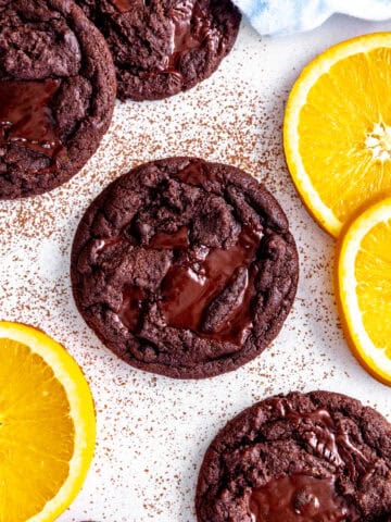 Orange chocolate cookie surrounded by fresh orange slices.