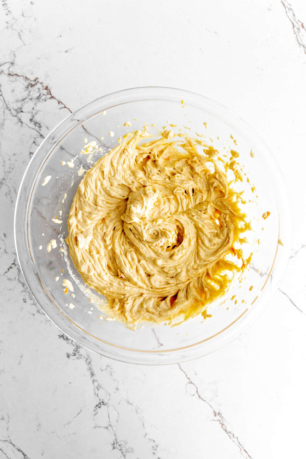 Creamed butter, sugar and orange juice in a glass bowl.