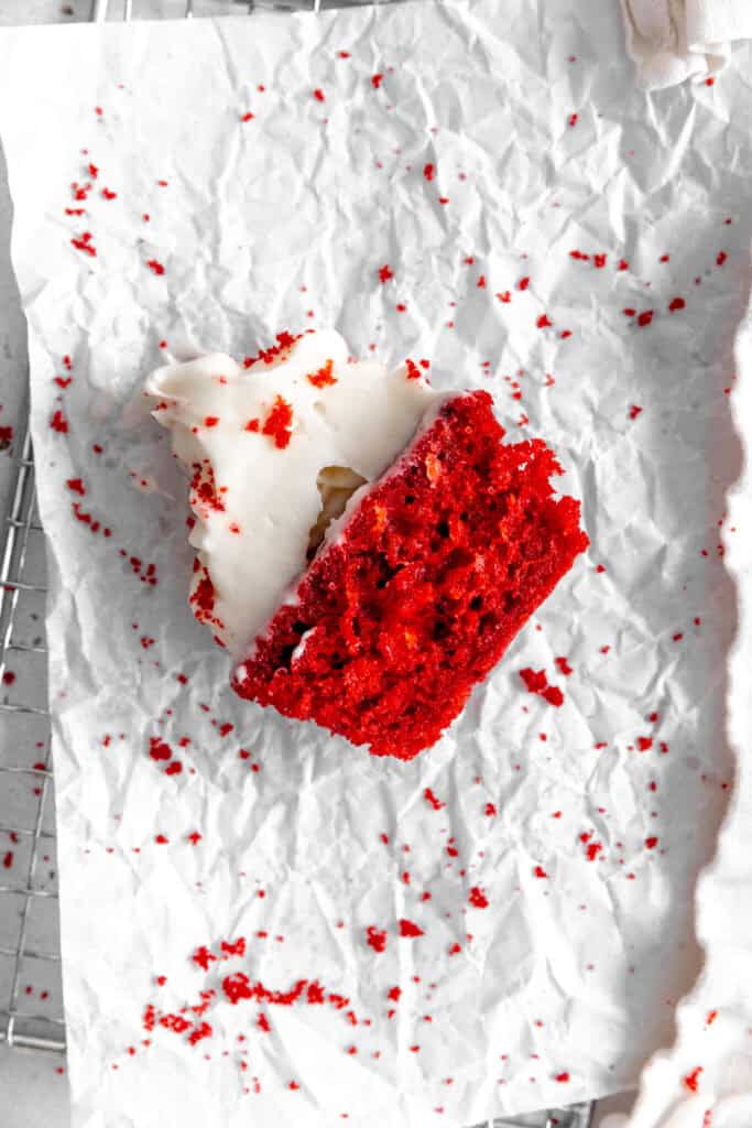 Half of a red velvet cupcake lying on a sheet of crumpled parchment paper.