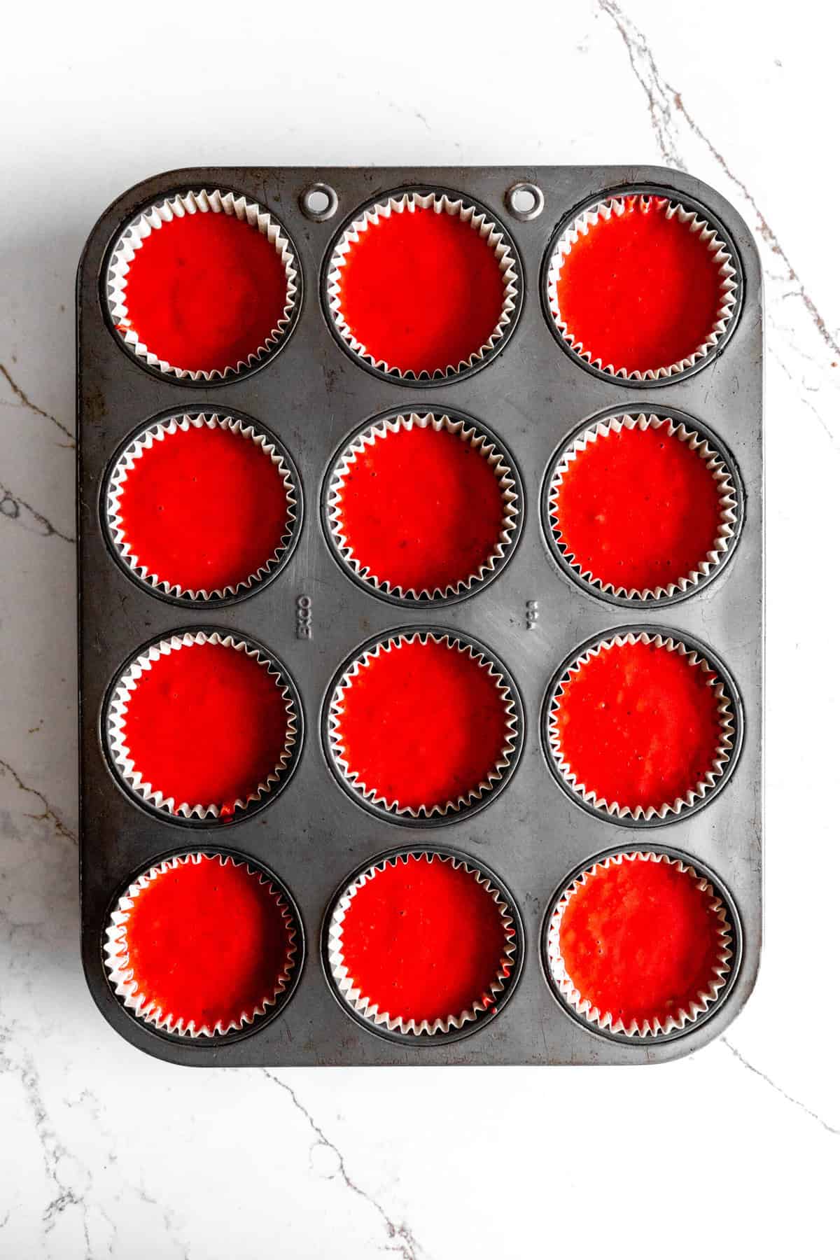 Unbaked red velvet cupcakes in a cupcake pan.