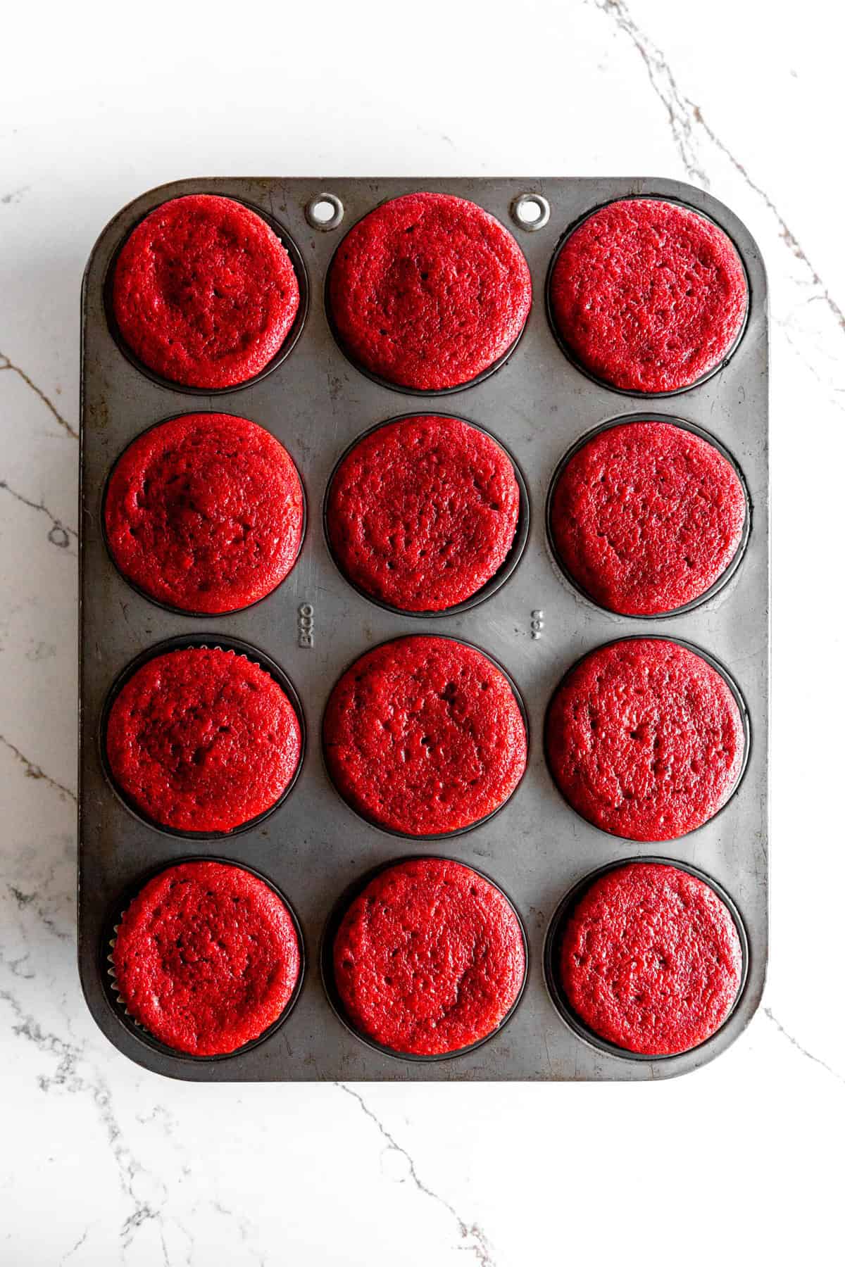 Baked red velvet cupcakes in a cupcake pan.