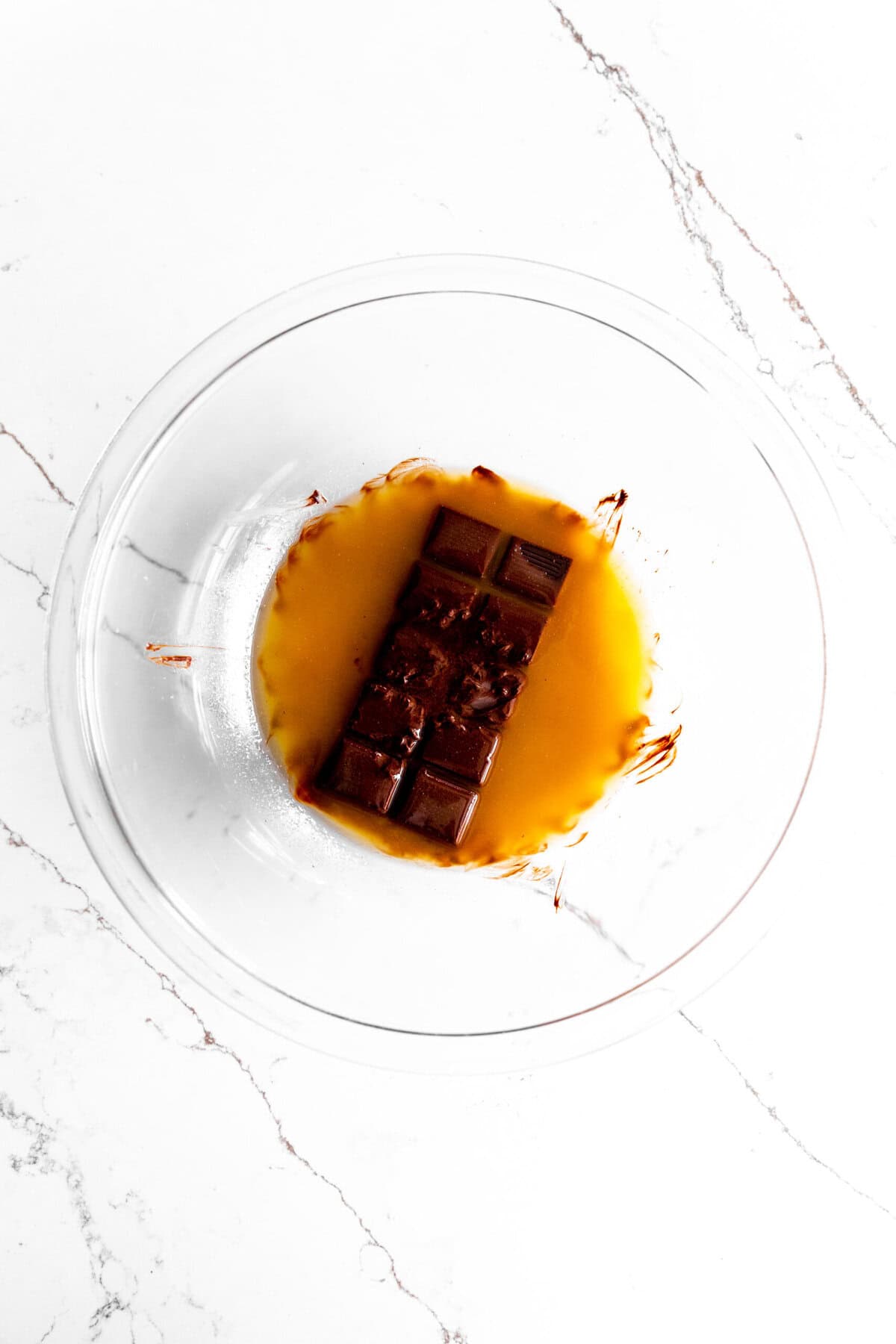 Melted butter poured over a chocolate bar in a glass bowl.