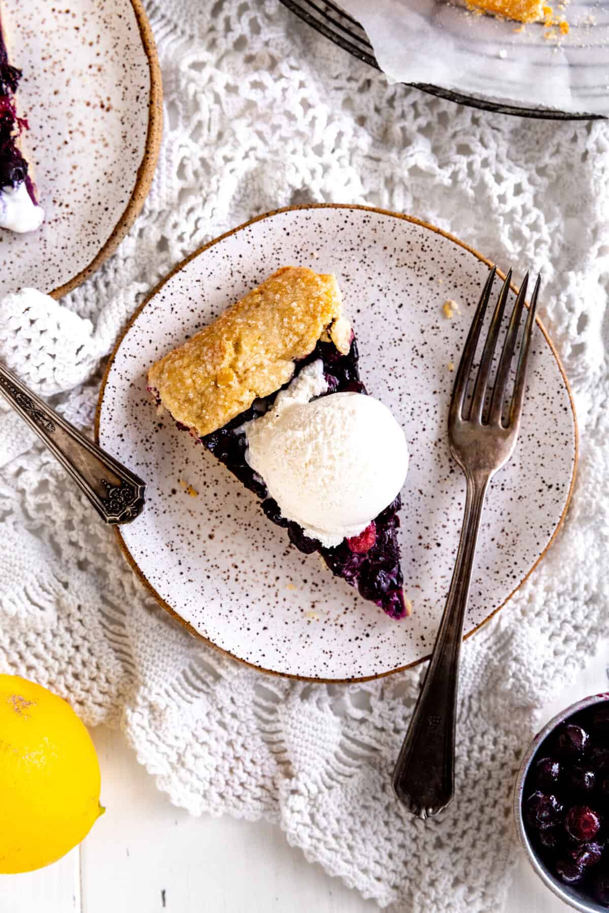 Slices of blueberry galette on white plates with forks.