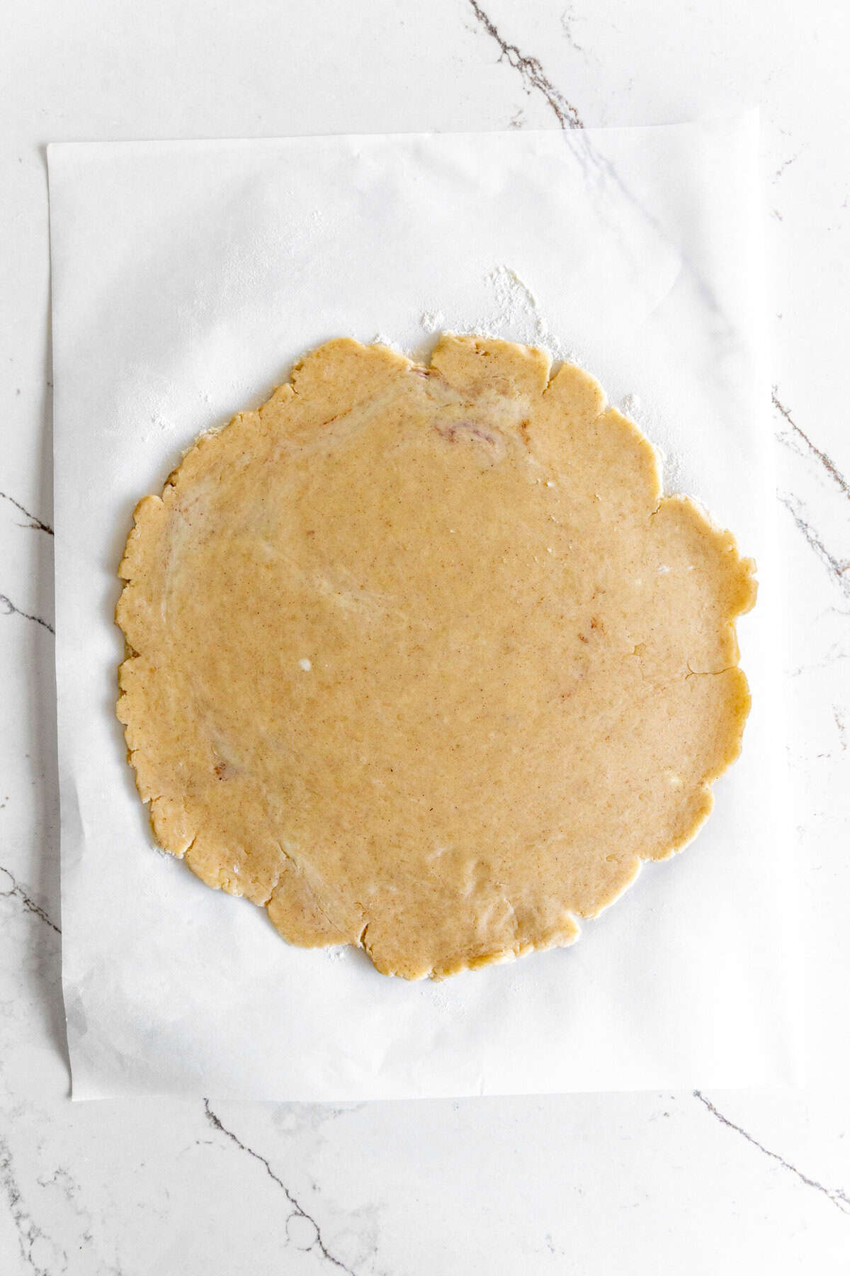 Piecrust rolled out on a sheet of parchment paper.