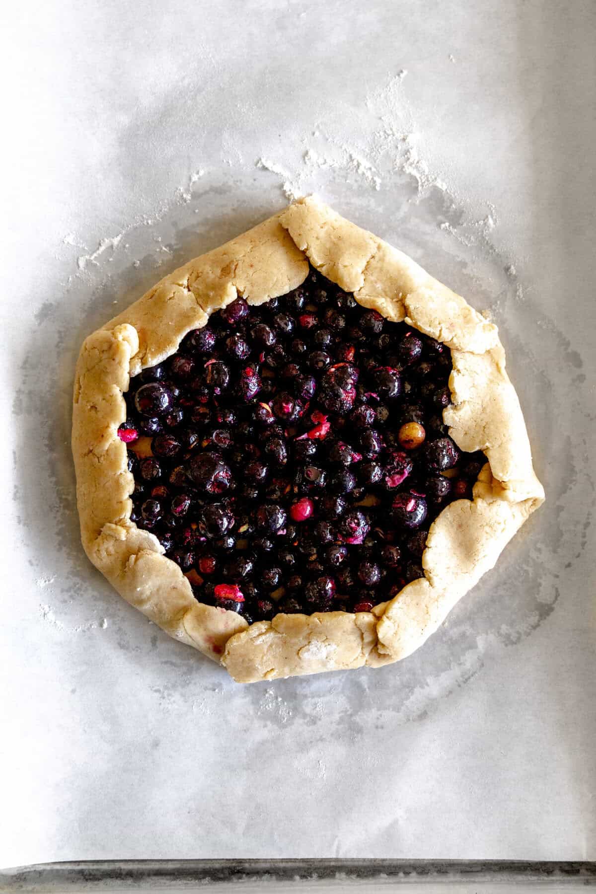 Unbaked, fully-folded blueberry galette.
