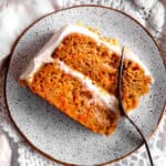 Fork cutting into a slice of carrot cake.