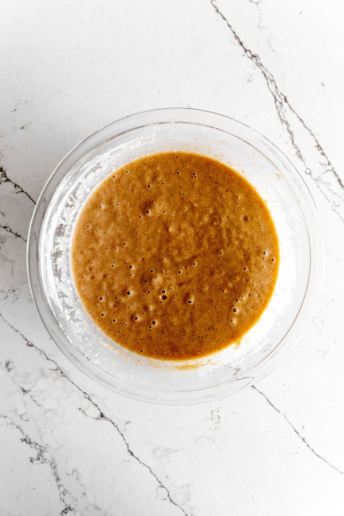 Wet, mixed carrot cake ingredients in a glass bowl.