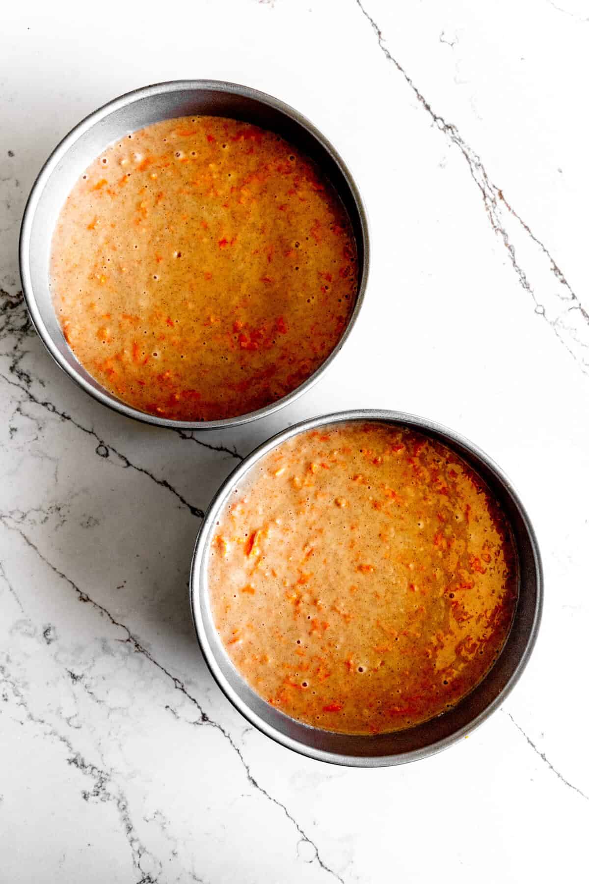 Unbaked carrot cake batter in two round cake pan.