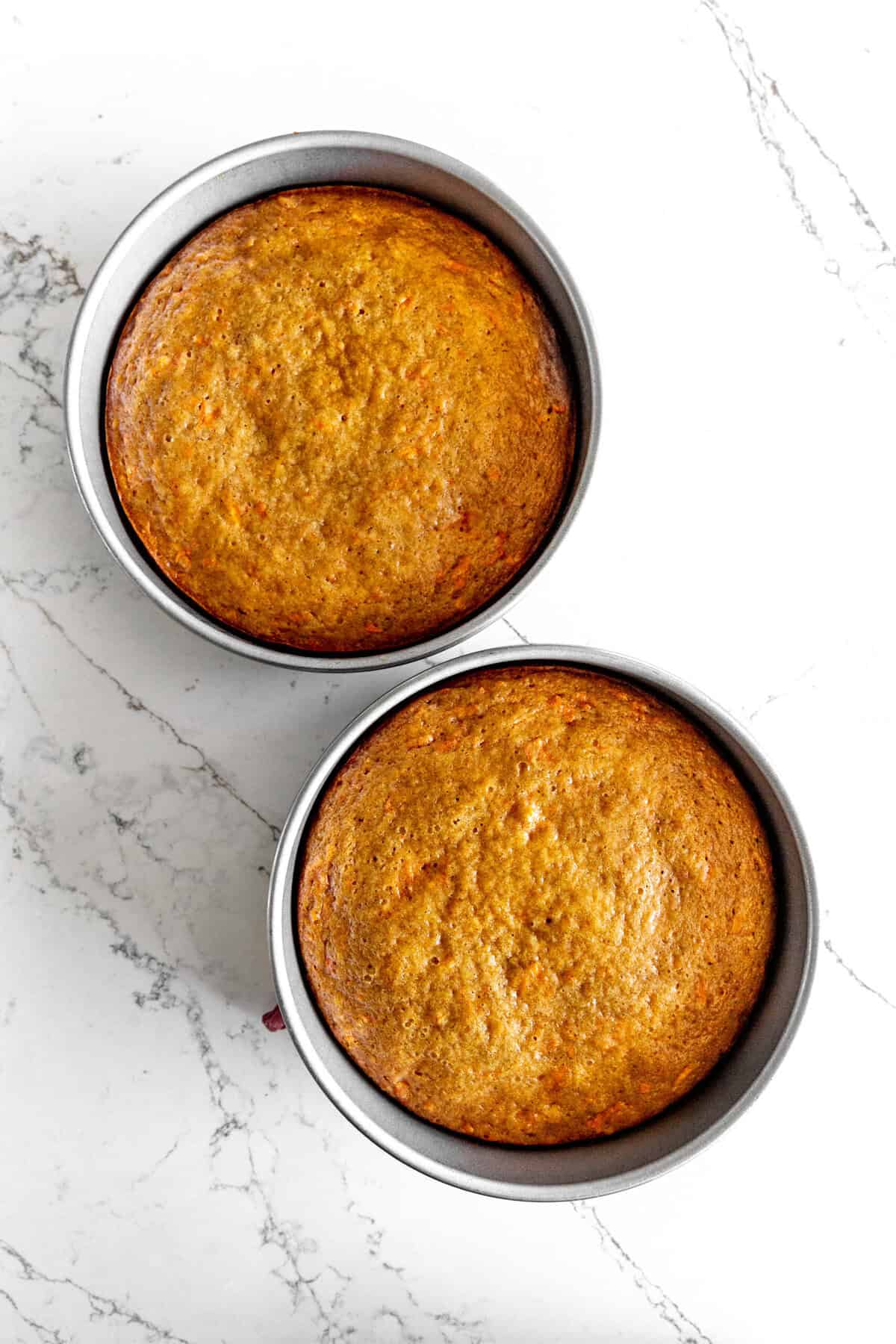 Baked carrot cake layers in two round cake pans.