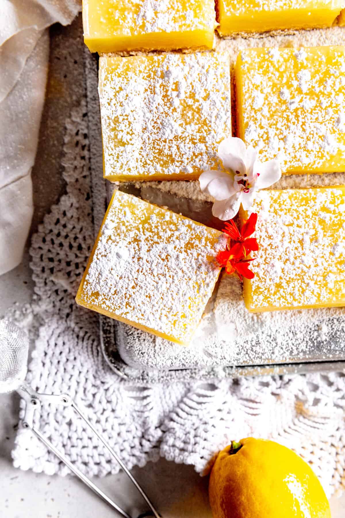 Lemon bars in a pan, a linen napkin and a whole lemon.