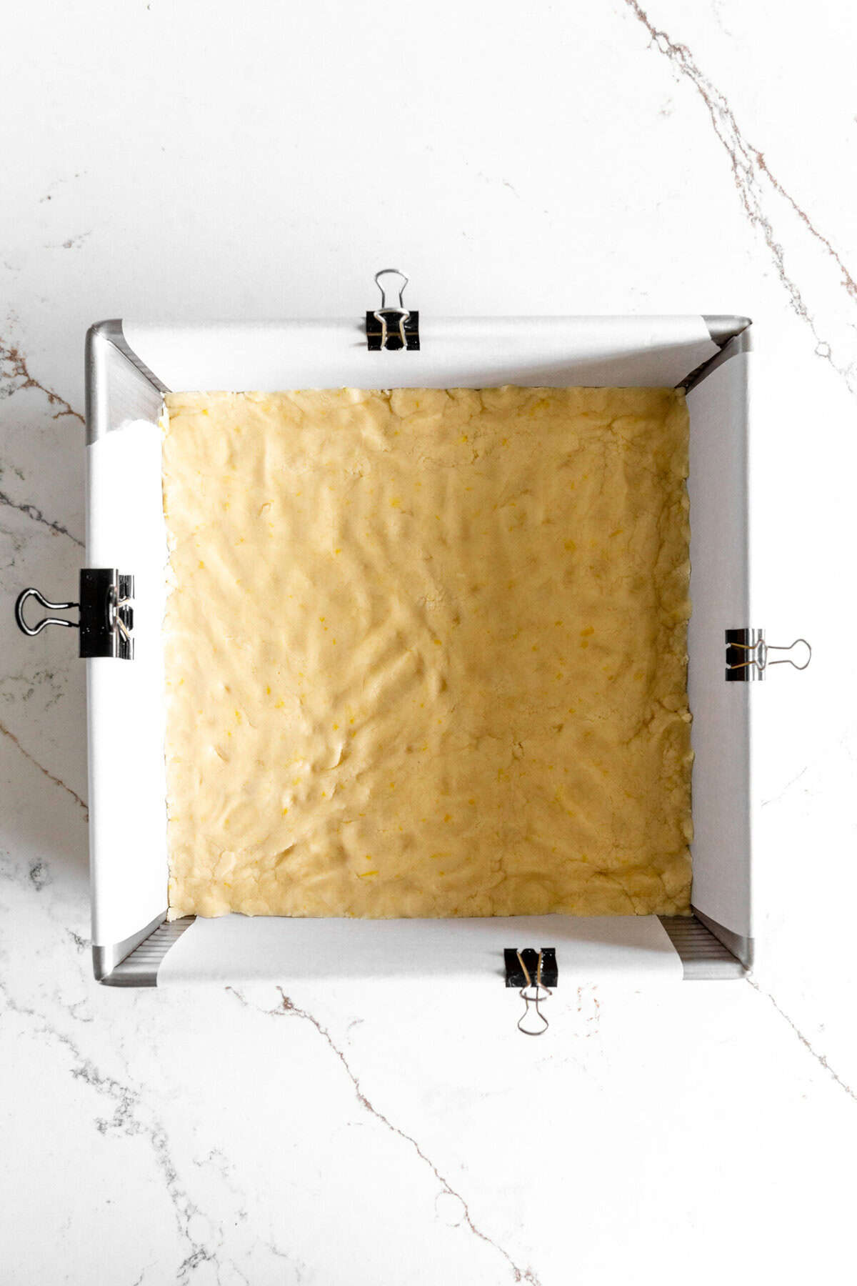 Shortbread dough pressed into a square pan.