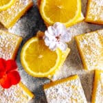 Lemon bars topped with powdered sugar and lemon slices.