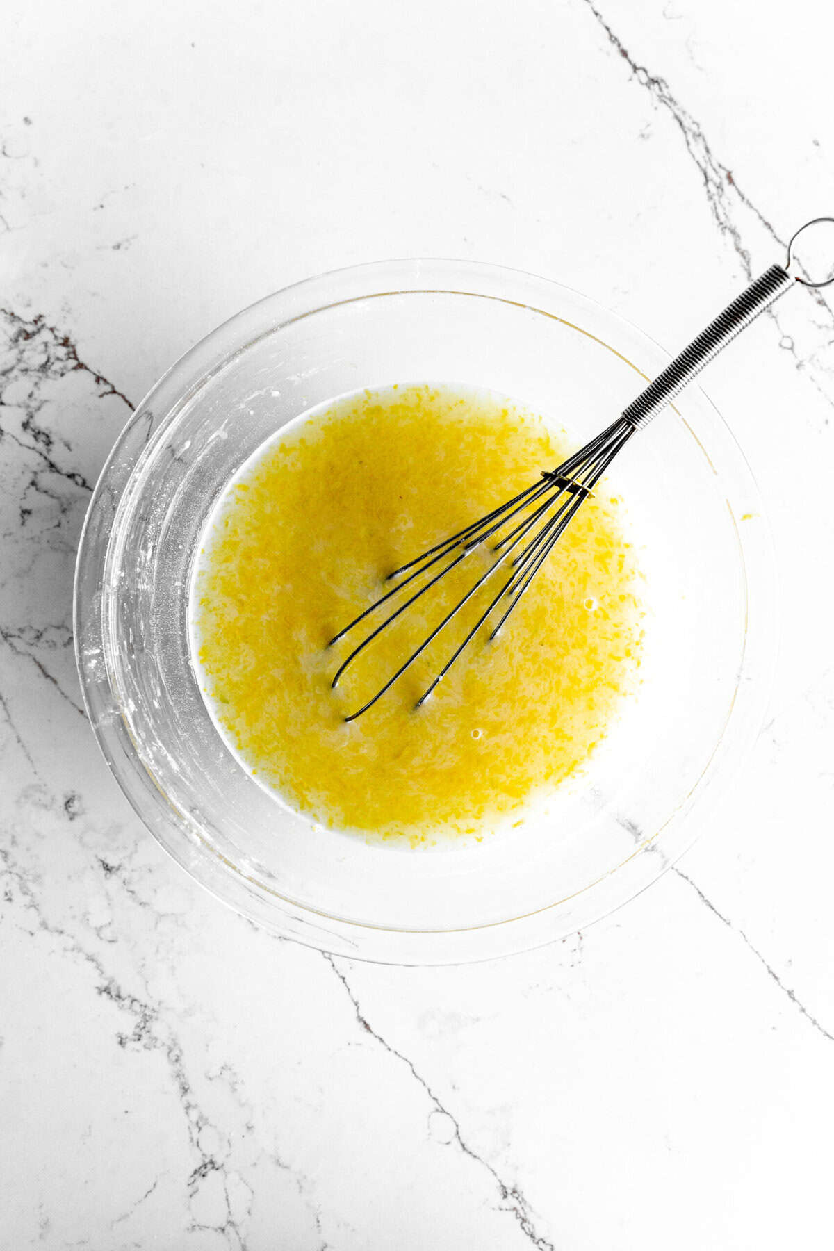 Glass bowl filled with sugar, lemon juice and a whisk.