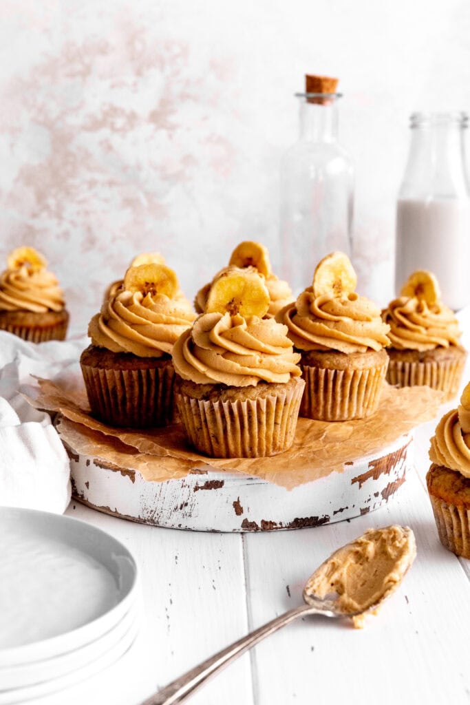 Peanut butter banana cupcakes, a stack of plates and a jug of milk.