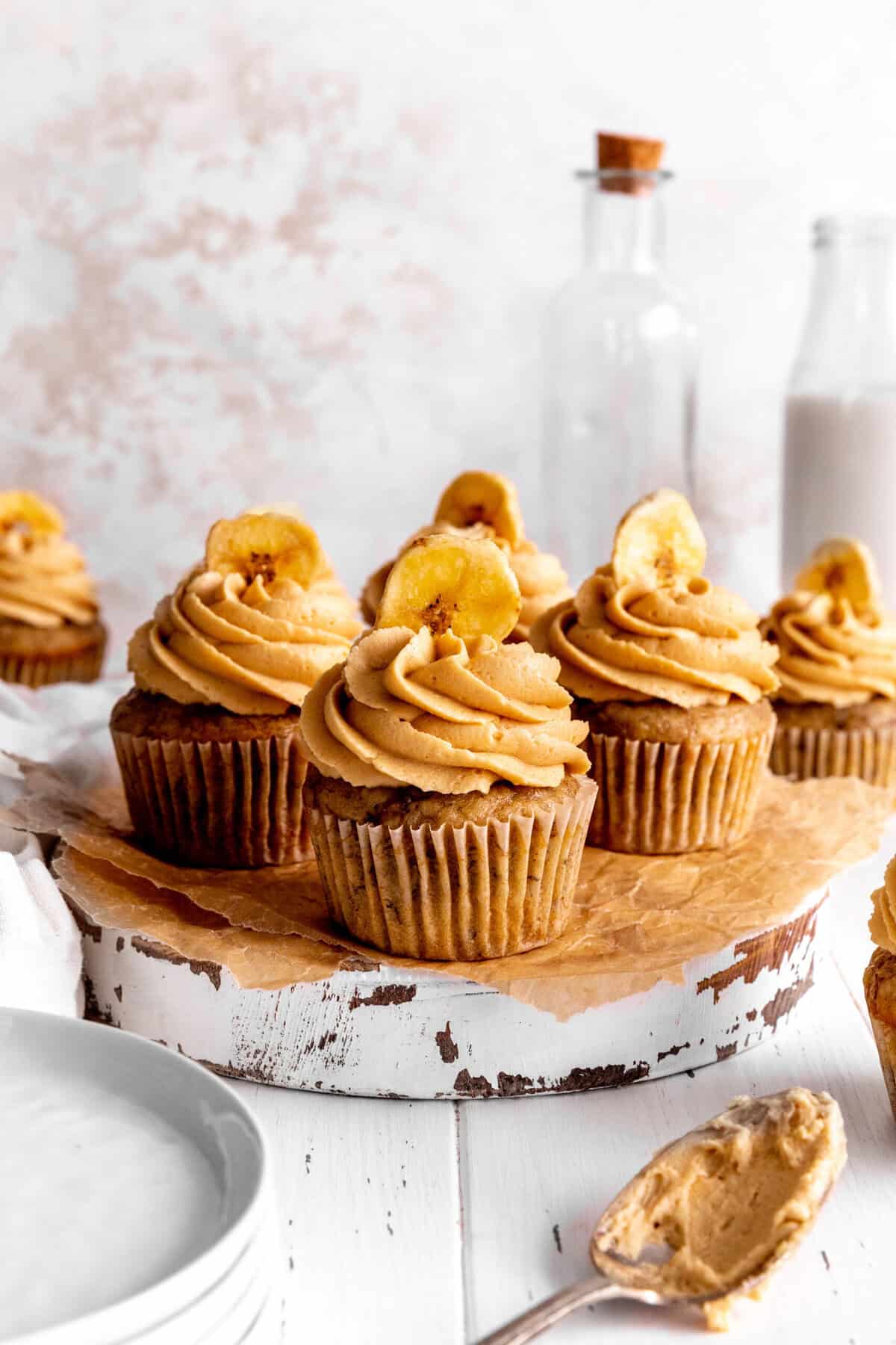 Peanut butter banana cupcakes, a stack of plates and a jug of milk.