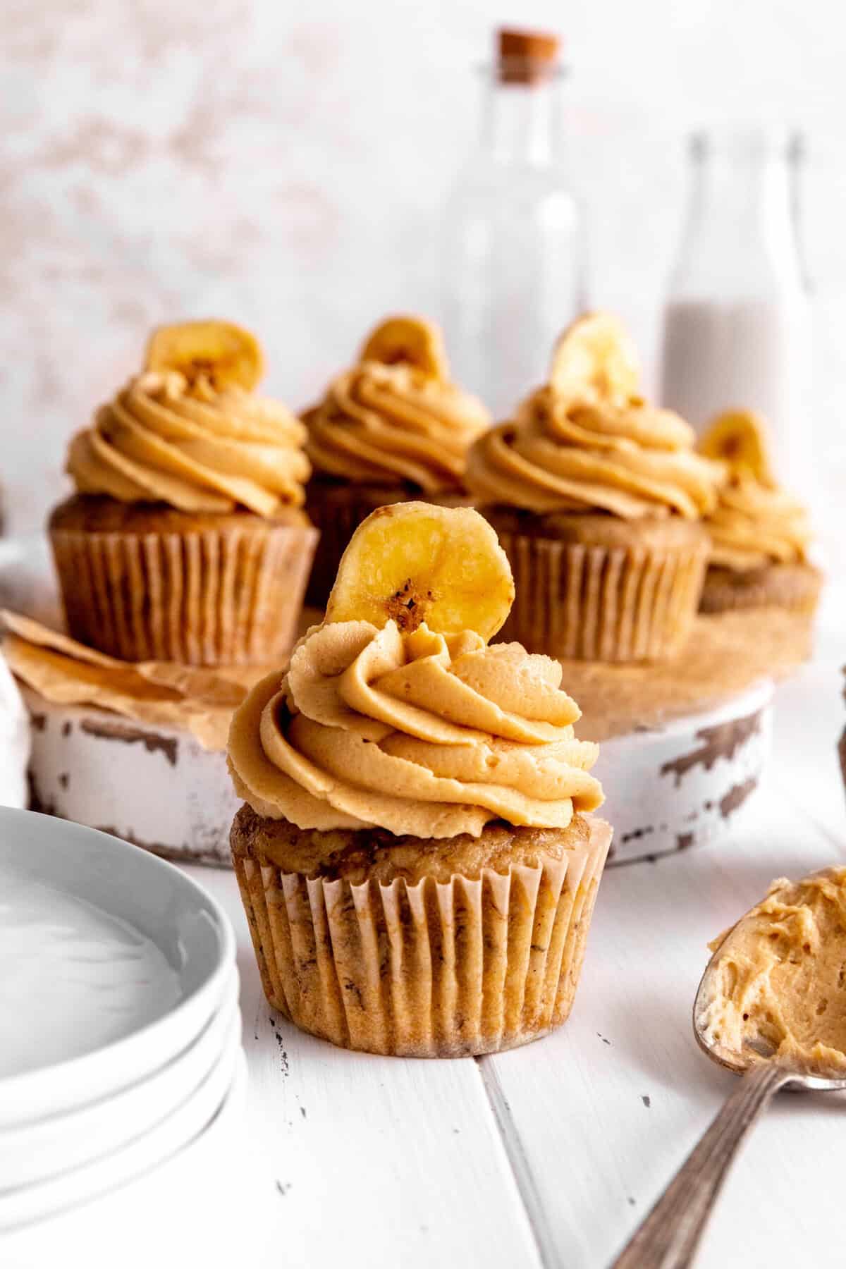 Peanut butter banana cupcake next to a stack of white plates.