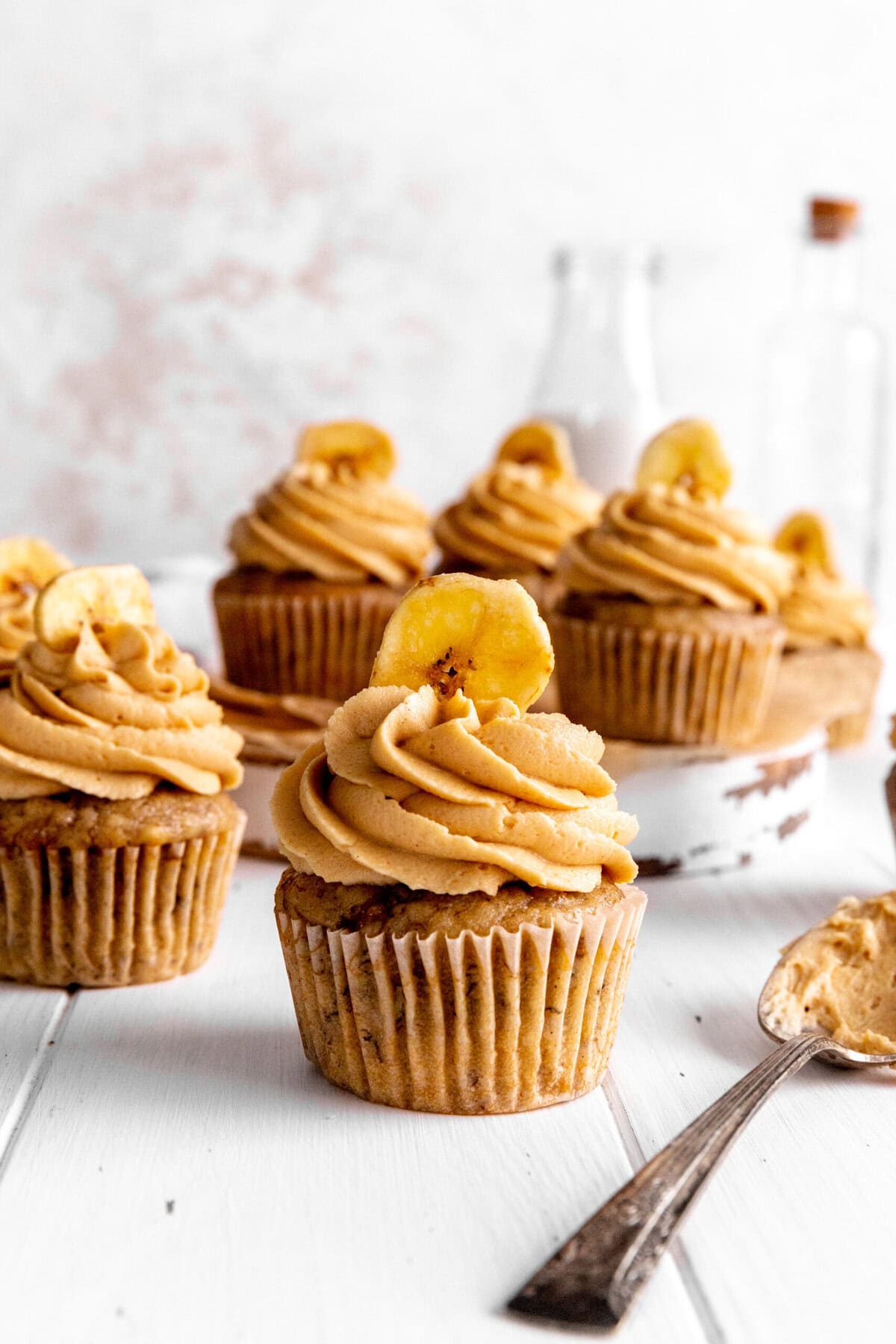 Peanut butter banana cupcakes, a spoon covered in frosting and a jug of milk.
