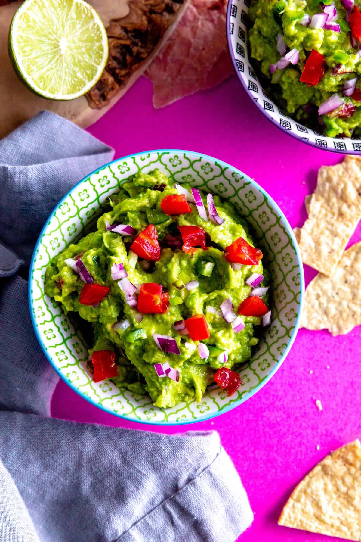 Bowl of guacamole, lime halves and a linen napkin.
