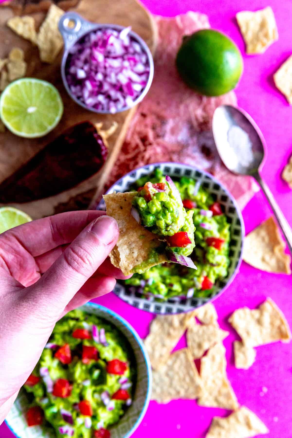 Hand holding a chip dipped in guacamole.