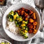 Bowl of spiced tofu, cucumber salsa and rice with forks and a napkin.