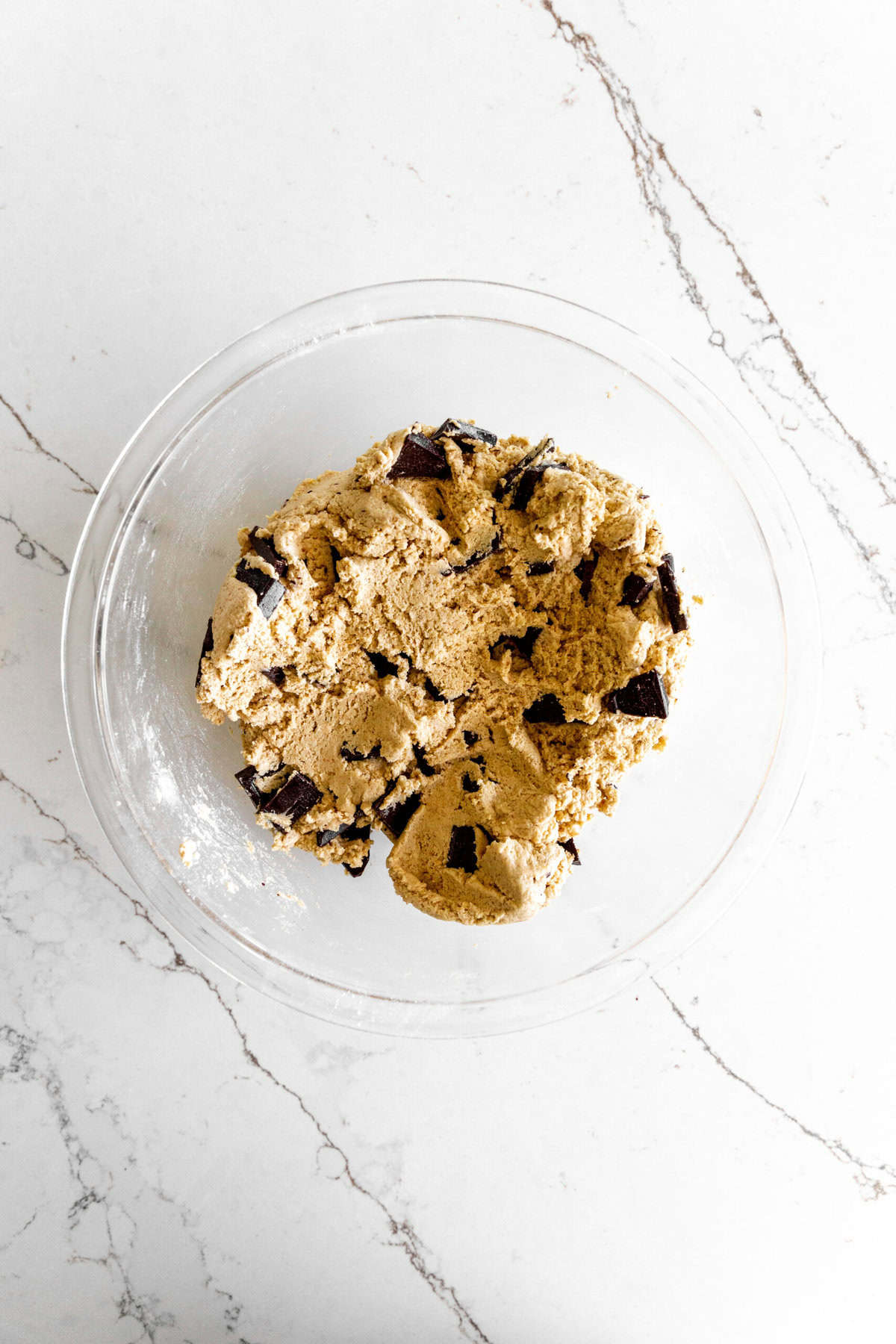 Cookie dough with chocolate chunks in a glass bowl.