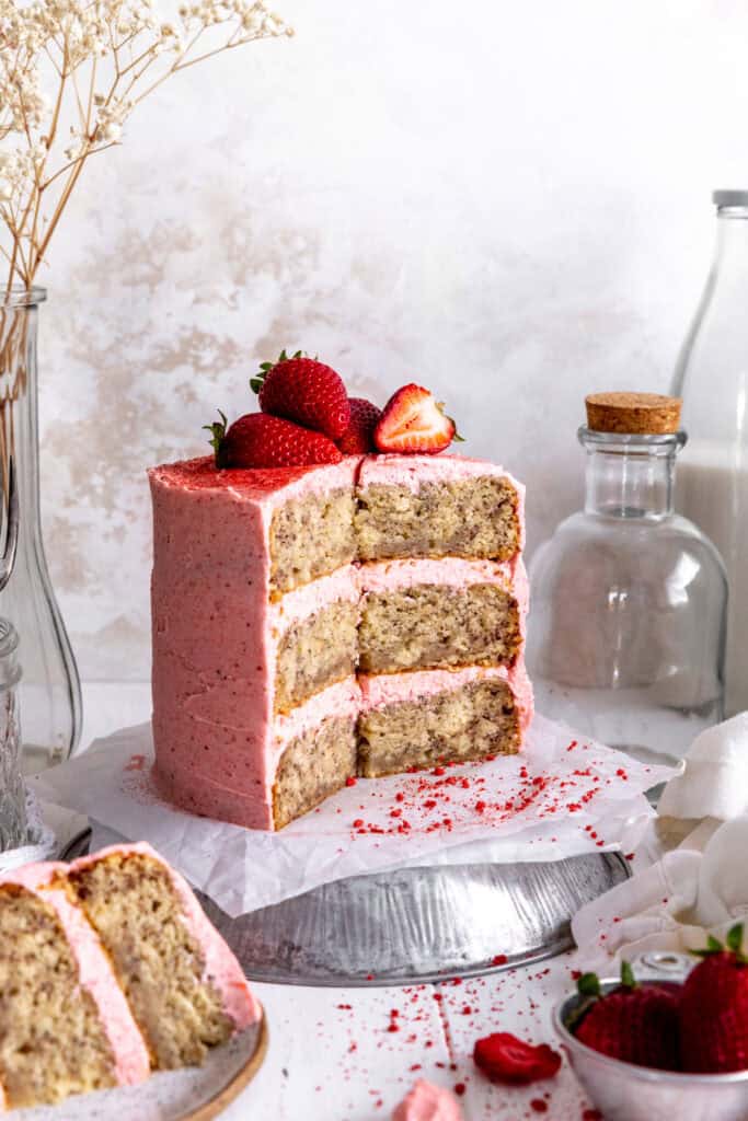 A strawberry banana cake with a slice taken out of it