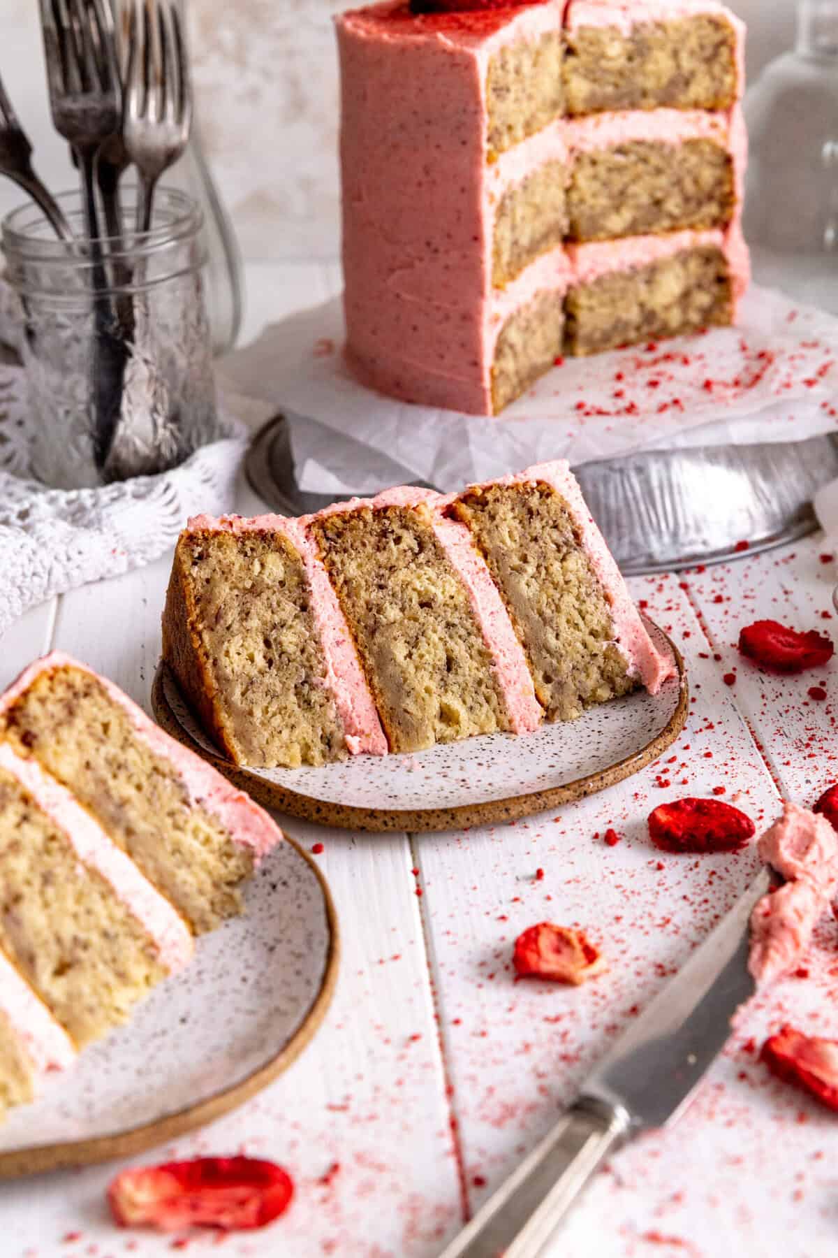 Two slices of strawberry cake on plates with a knife.